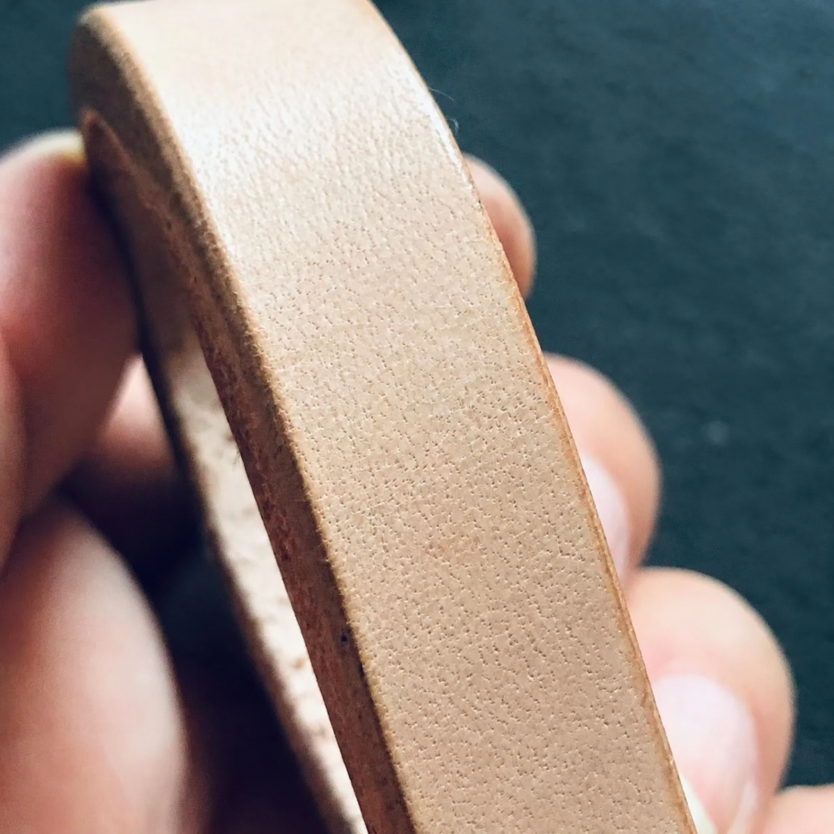 Raw edge of the undyed leather strap held in hand