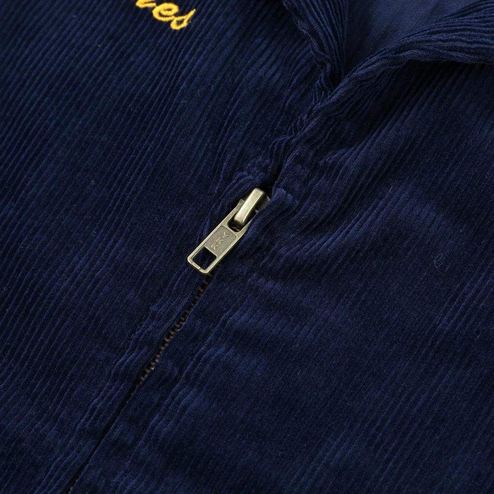 Close-up of the brass YKK zipper and chest embroidery on the Rider Corduroy Jacket in Navy