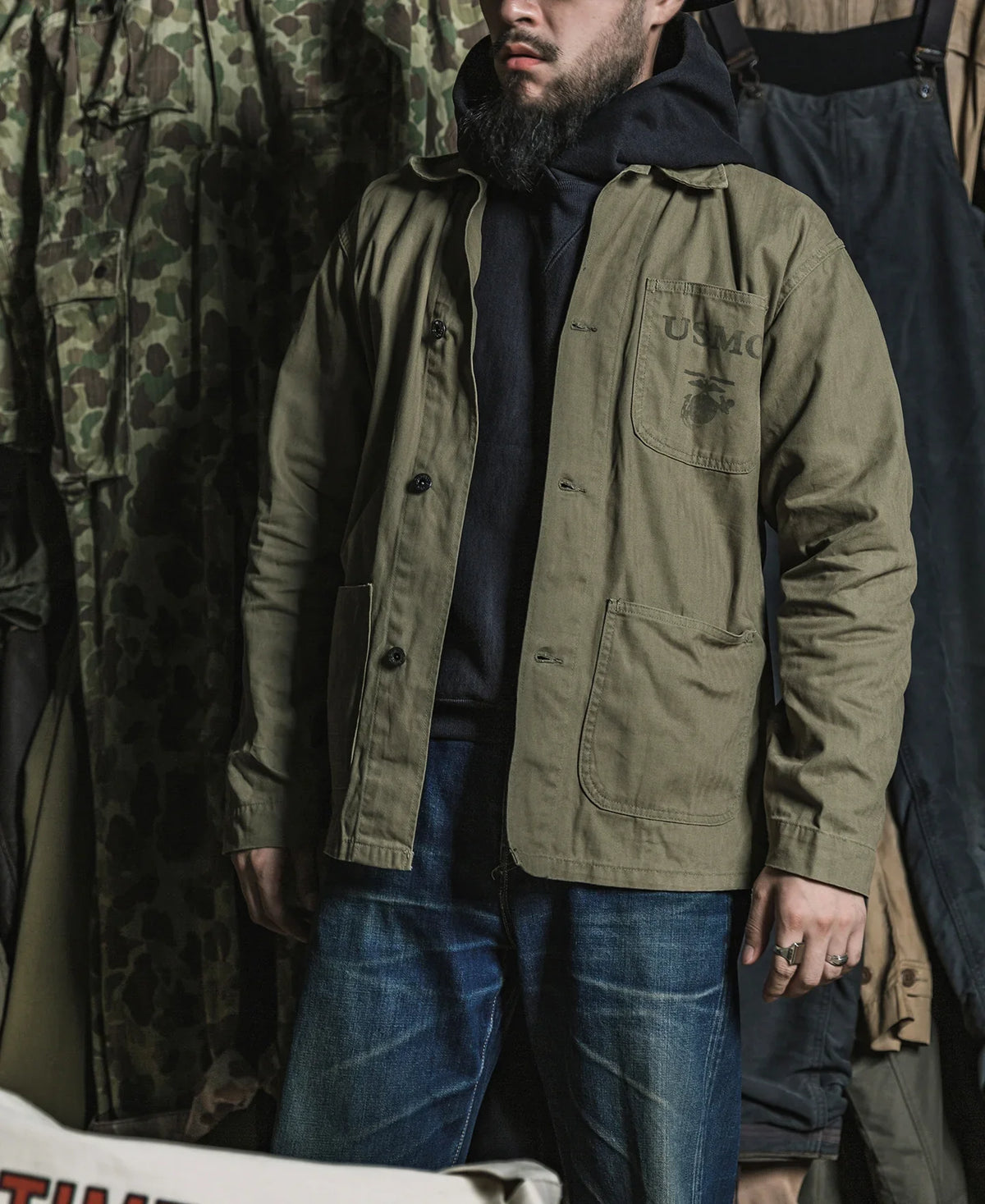 Man wearing the P41 jacket over a navy hoodie and jeans in a vintage shop
