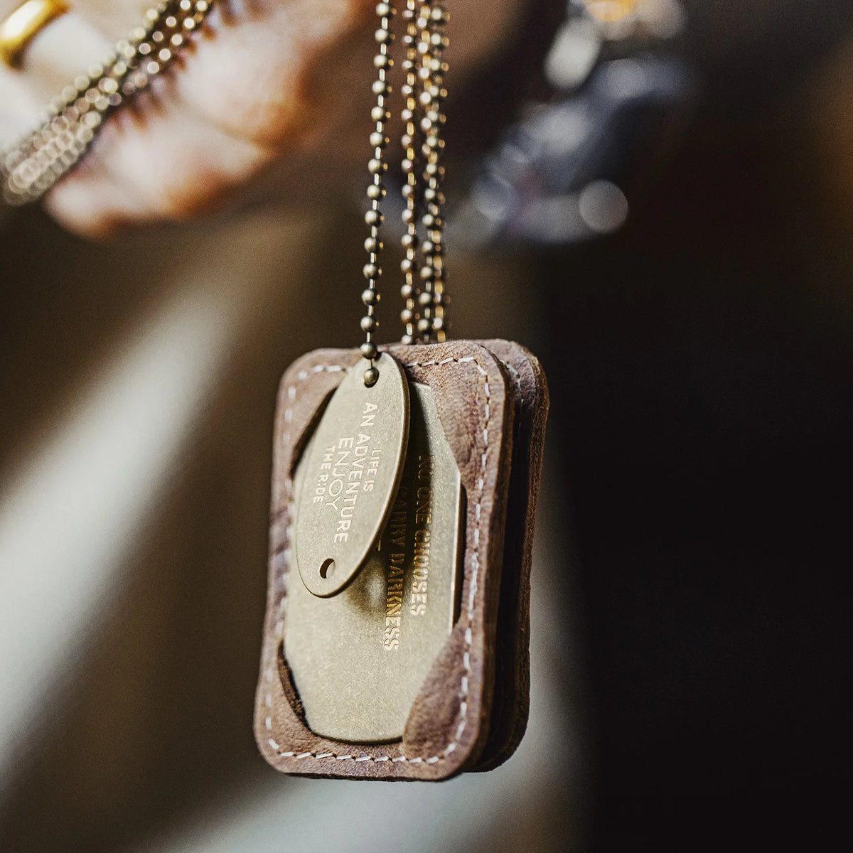 Tag necklace hanging from the hand, tags in the leather holder on the ball chains