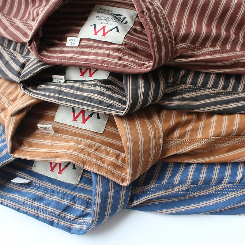 The four stripes folded and stacked, Graphite, Terracotta, Mustard and Blue, showing collars and inside labels