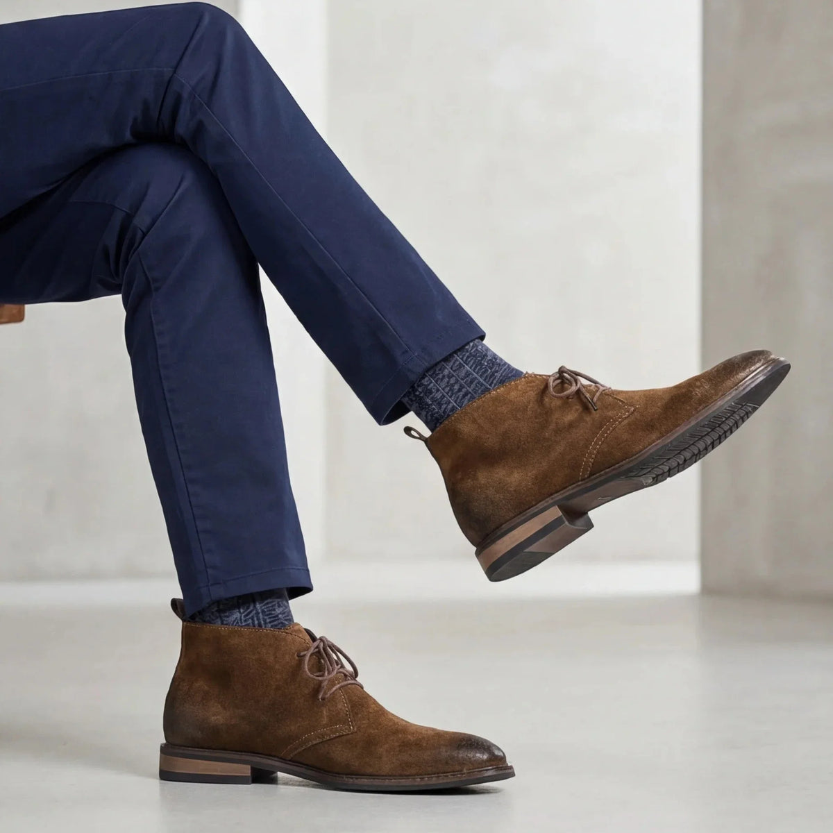 Pampa Suede Chukka Boot with navy trousers and wool socks, legs crossed