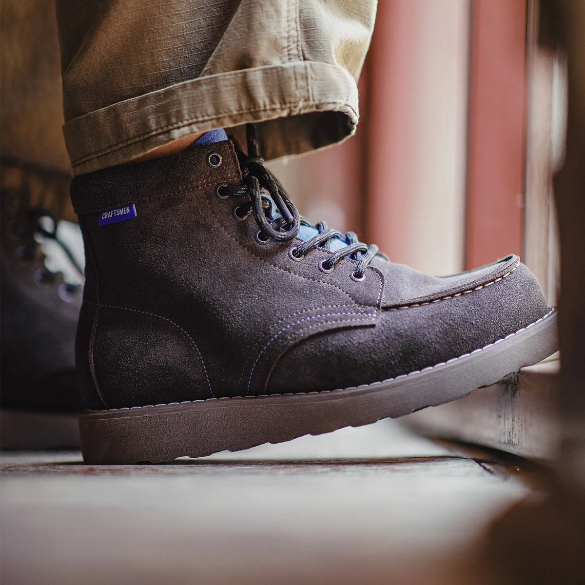 Boot worn with khaki trousers, side view on a wooden step