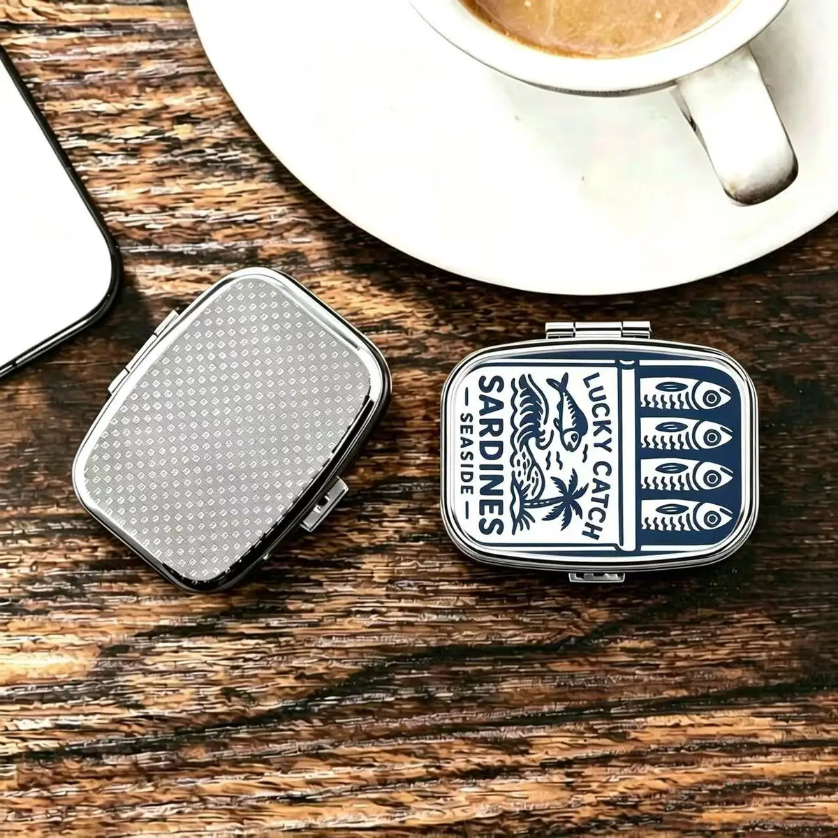 Two tins on a wooden surface, one showing the printed lid and one the textured metal back