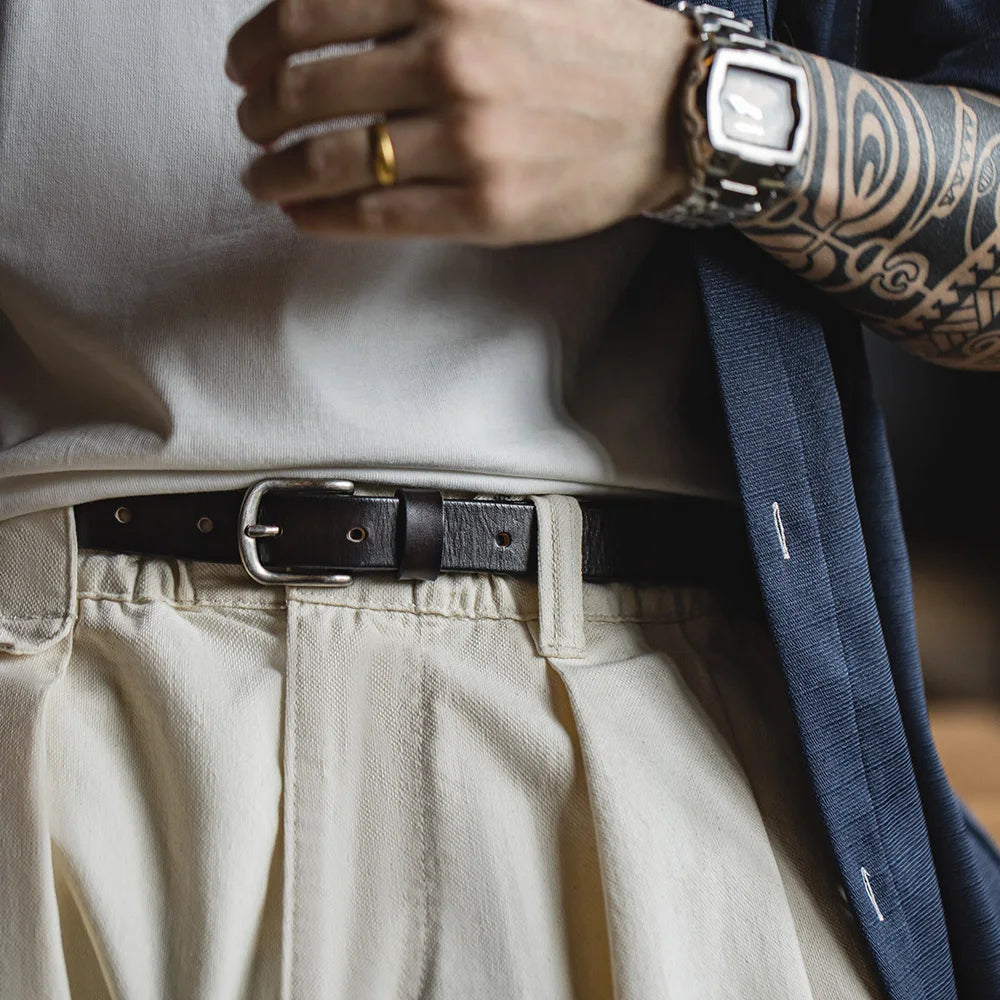 Close view of the belt at the waist showing the oval buckle and leather keeper