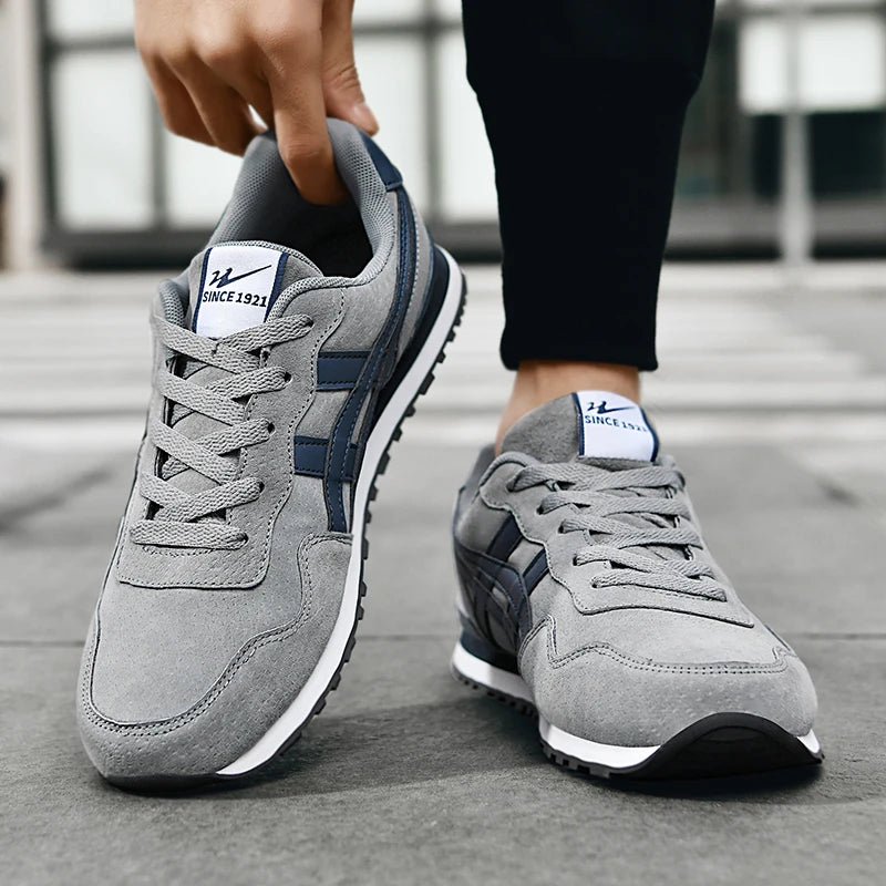 Grey and Navy sneaker worn, hand pulling the heel tab to show the reinforced counter