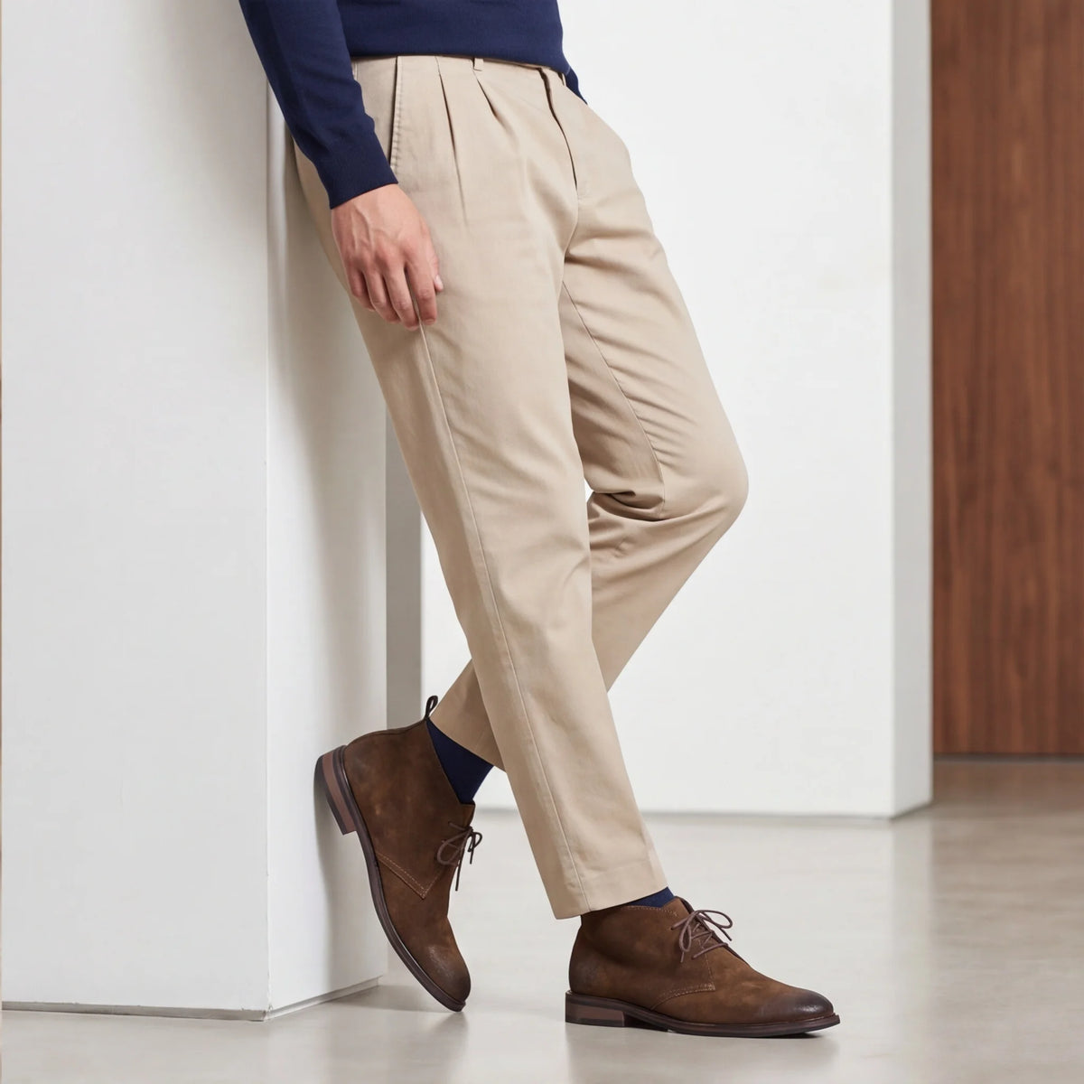 Pampa Suede Chukka Boot with beige trousers, leaning on a wall