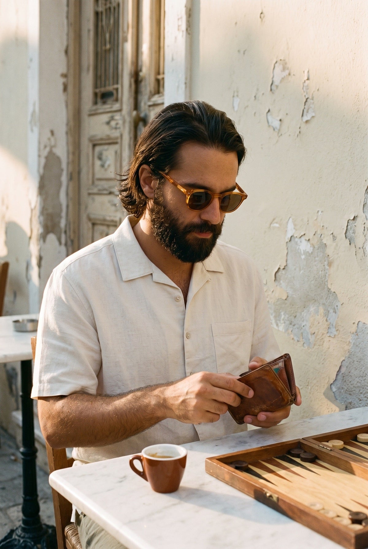 Man wearing the Ecru Dockworker shirt at a cafe table playing backgammon
